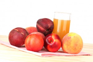 Ripe peaches and juice on wooden table on white background